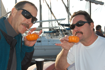 Two men sipping cocktails from tiny carved pumpkins