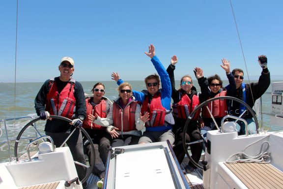 Seven people waving on a sailboat
